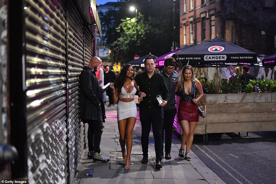 30403212-8490751-MANCHESTER_Two_couples_walk_past_bars_on_Thomas_Street_in_the_No-a-148_1593930321904.jpg
